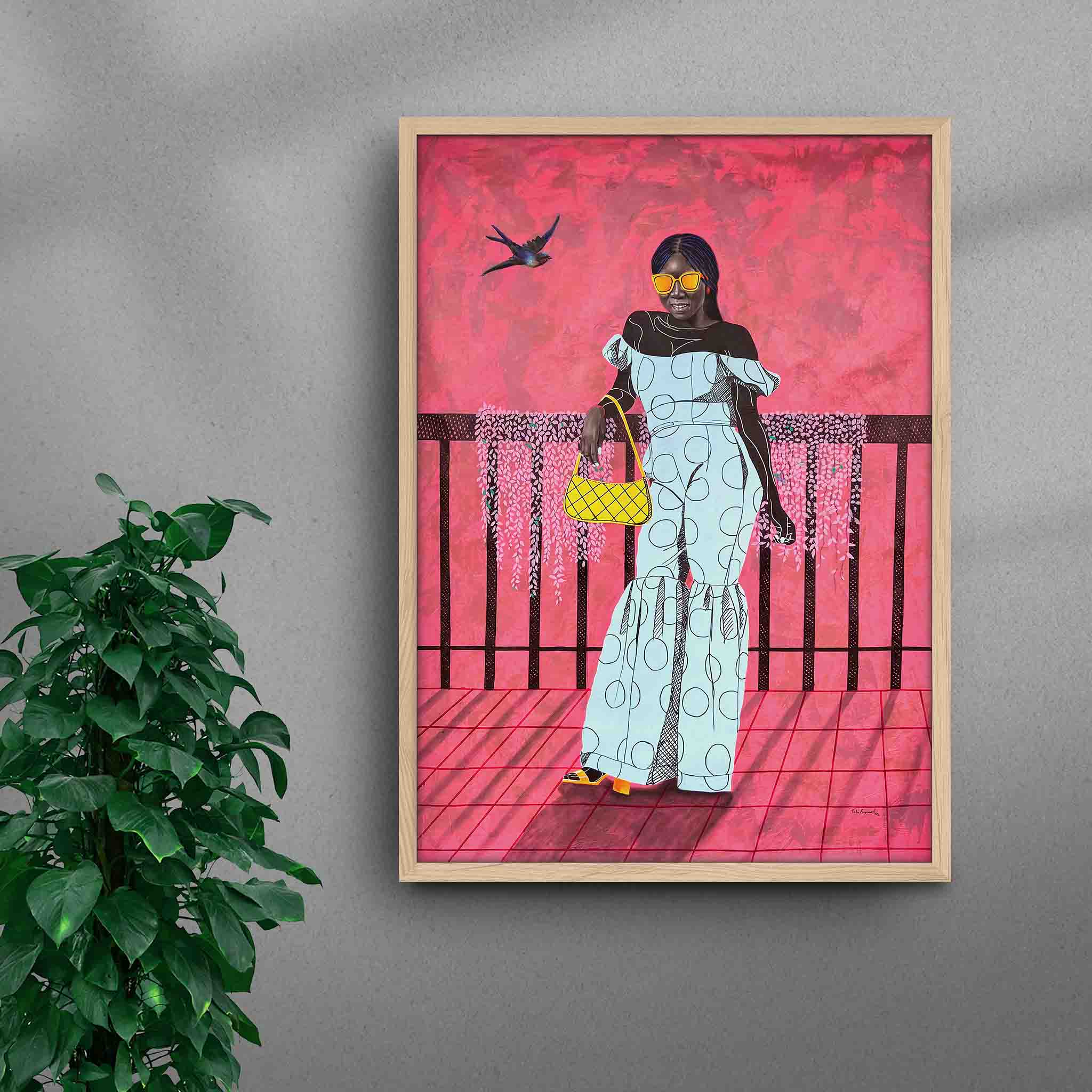 Framed A La Mode 1 black art print by Tolu Raymond, a contemporary African artwork featuring an African lady in an elegant blue outfit, set against a bold pink background with striking sunglasses and a yellow handbag, in a natural wood frame